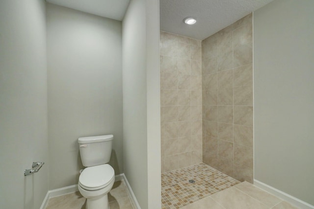 bathroom with tiled shower, tile patterned floors, a textured ceiling, and toilet