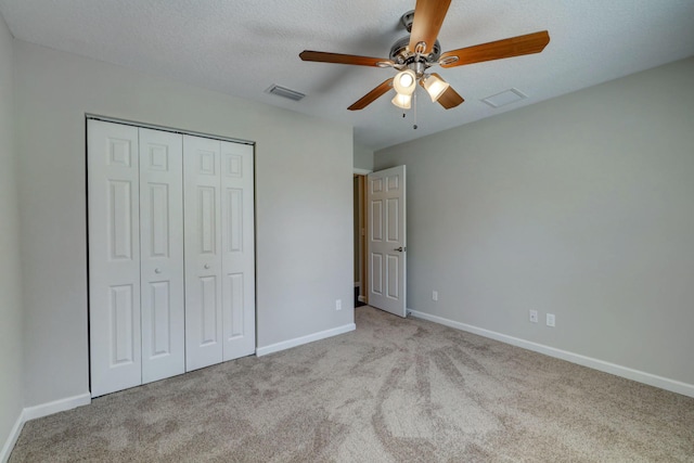 unfurnished bedroom with ceiling fan, light carpet, a textured ceiling, and a closet