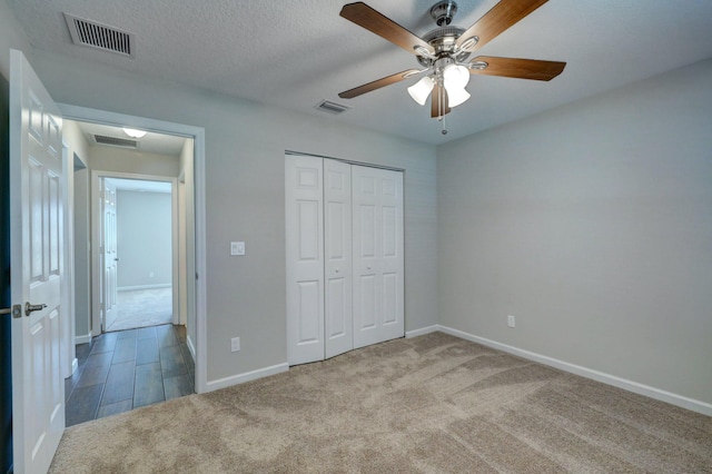 unfurnished bedroom featuring light carpet, ceiling fan, a closet, and a textured ceiling