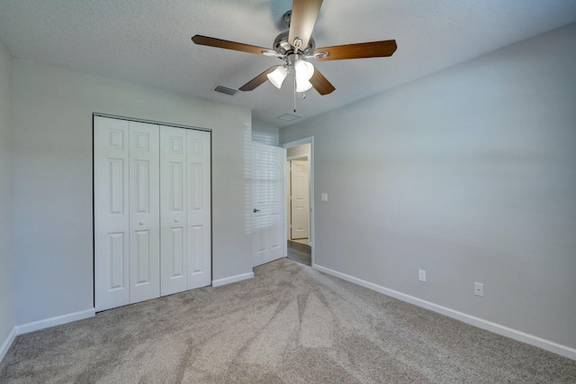 unfurnished bedroom with ceiling fan, light colored carpet, a closet, and a textured ceiling