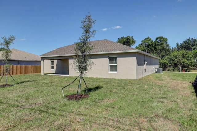 rear view of house with central AC unit and a lawn