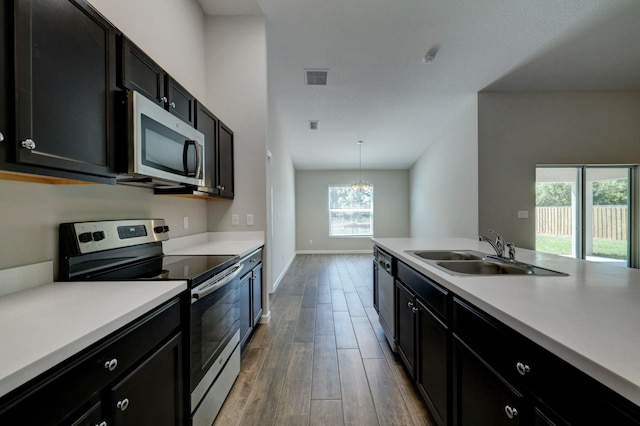 kitchen with pendant lighting, wood-type flooring, sink, a notable chandelier, and stainless steel appliances