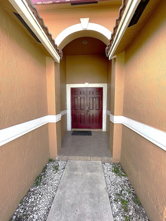 entrance to property featuring a tile roof and stucco siding