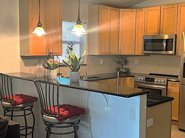 kitchen with tasteful backsplash, appliances with stainless steel finishes, a breakfast bar, a peninsula, and hanging light fixtures