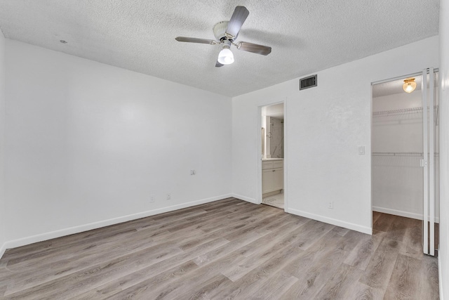 21894 Lake Forest Cir Unit 204, Boca Raton, FL 33433 - unfurnished bedroom with light wood-type flooring, connected bathroom, a closet, a textured ceiling, and a spacious closet