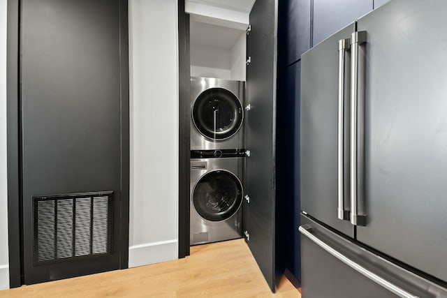 laundry room featuring stacked washer / drying machine and light hardwood / wood-style flooring