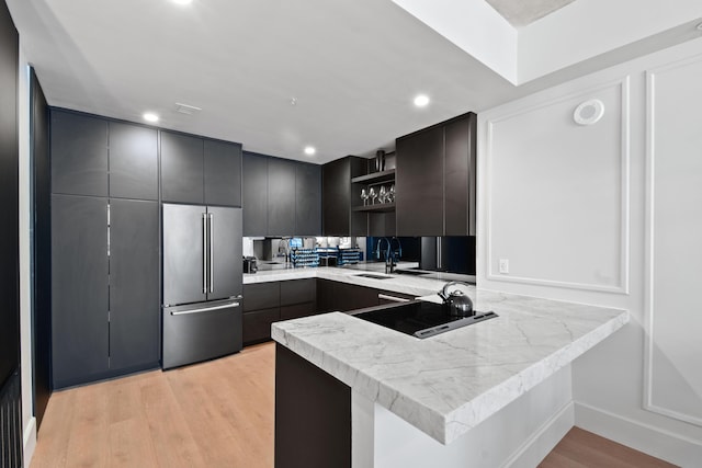 kitchen with high quality fridge, sink, kitchen peninsula, and light hardwood / wood-style floors