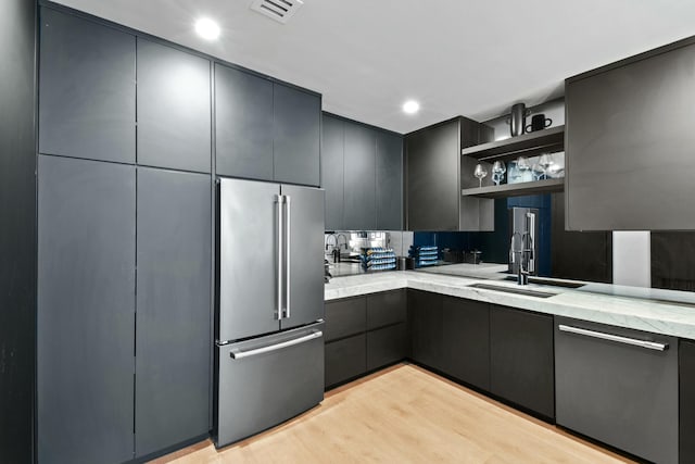 kitchen featuring light stone counters, sink, light hardwood / wood-style floors, and appliances with stainless steel finishes