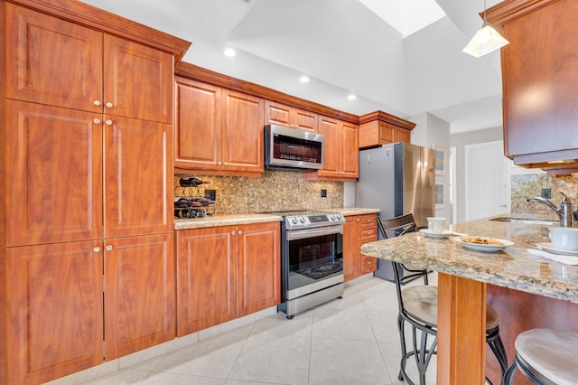 kitchen featuring a kitchen breakfast bar, stainless steel appliances, light tile patterned flooring, pendant lighting, and sink