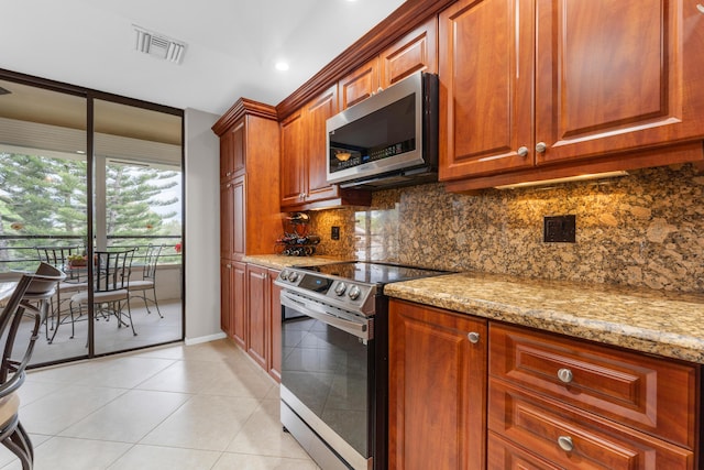 kitchen featuring light tile patterned floors, a wall of windows, stainless steel appliances, light stone countertops, and tasteful backsplash