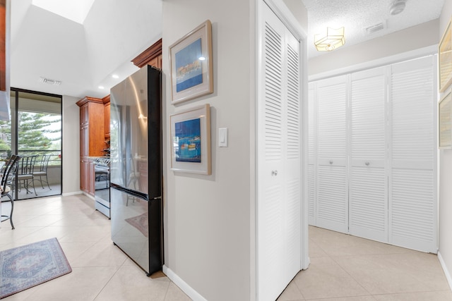 corridor with a textured ceiling, floor to ceiling windows, and light tile patterned flooring