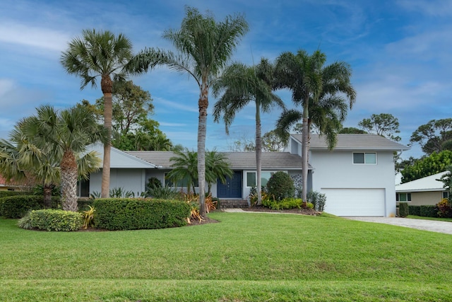 view of front of home with driveway, an attached garage, a front lawn, and stucco siding