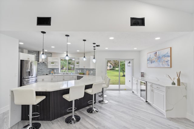 kitchen with white cabinetry, stainless steel fridge with ice dispenser, kitchen peninsula, and a breakfast bar