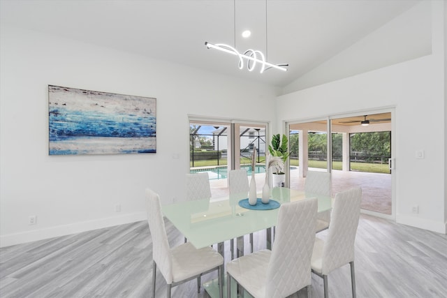 dining room featuring light hardwood / wood-style flooring, high vaulted ceiling, and a chandelier