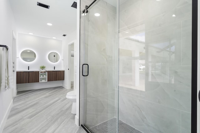 bathroom with vanity, toilet, a shower with shower door, and wood-type flooring