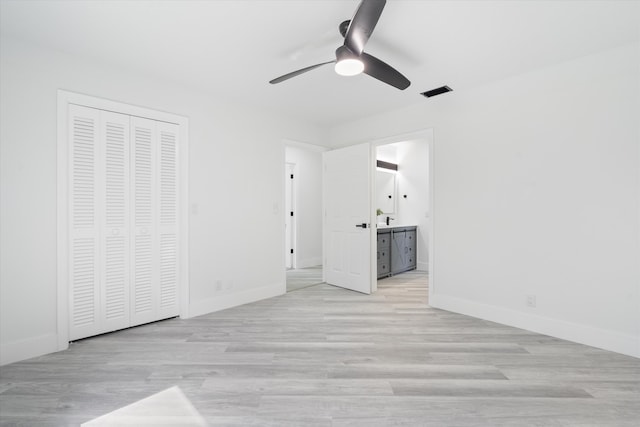 unfurnished bedroom with ceiling fan, ensuite bath, a closet, and light wood-type flooring