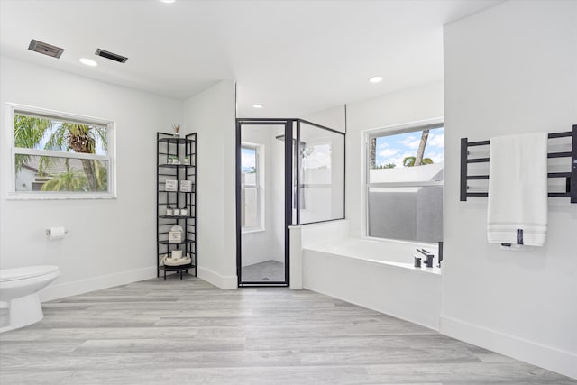 bathroom featuring hardwood / wood-style floors, a wealth of natural light, plus walk in shower, and toilet