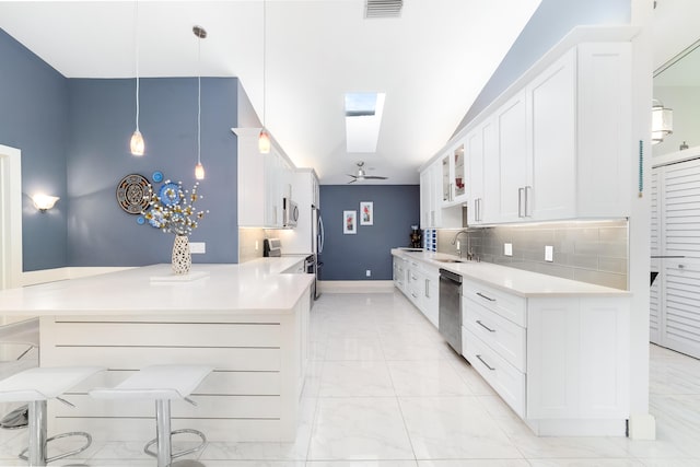 kitchen with sink, tasteful backsplash, hanging light fixtures, appliances with stainless steel finishes, and white cabinets