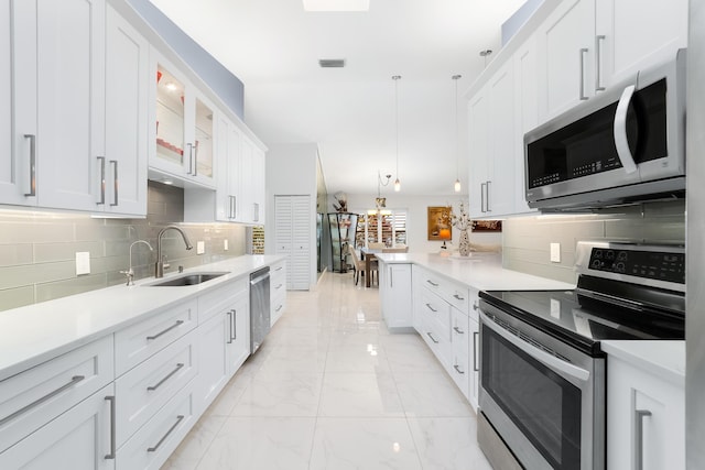 kitchen with sink, white cabinetry, decorative light fixtures, stainless steel appliances, and decorative backsplash