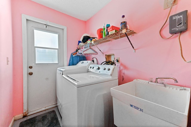 washroom featuring washing machine and dryer, baseboards, a sink, and laundry area