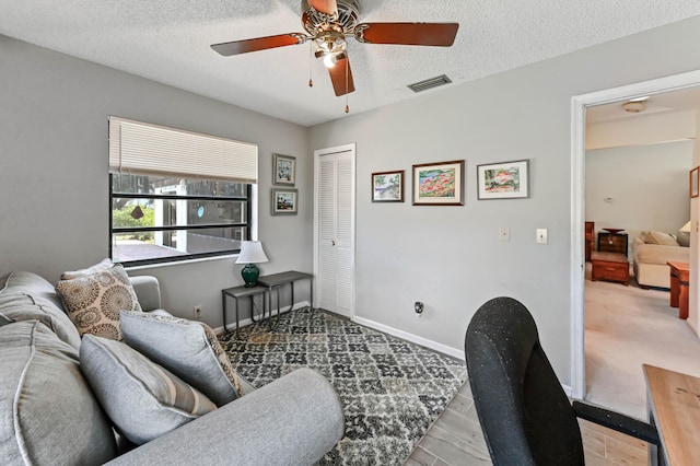 office area with baseboards, a ceiling fan, visible vents, and a textured ceiling