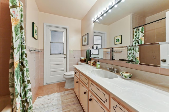 full bath featuring tile patterned floors, toilet, tile walls, curtained shower, and vanity