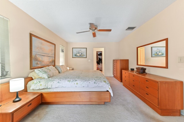 bedroom featuring light colored carpet, a ceiling fan, visible vents, and a spacious closet
