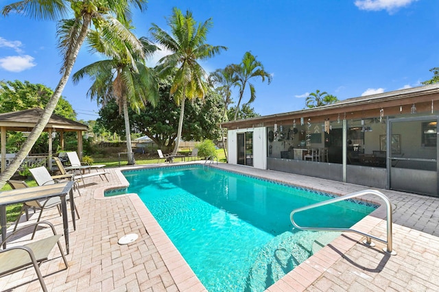 pool with a gazebo, a patio area, a sunroom, and fence