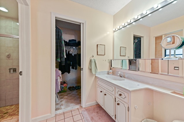 full bathroom featuring a spacious closet, vanity, tile patterned floors, and tiled shower