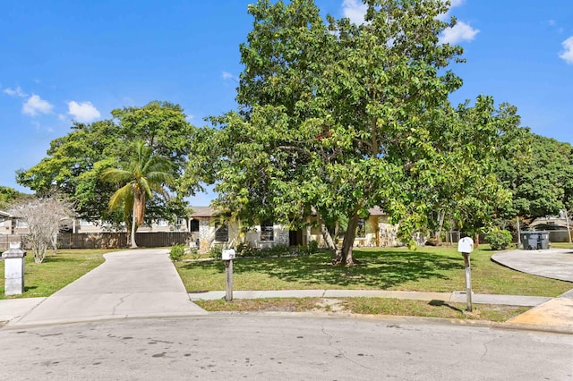 obstructed view of property with driveway, a front yard, and fence
