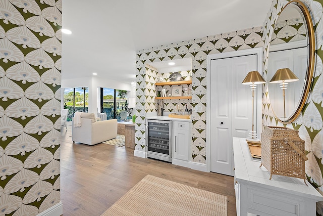 bar featuring wine cooler and light hardwood / wood-style flooring