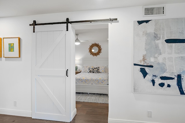 bedroom with a barn door and dark hardwood / wood-style flooring