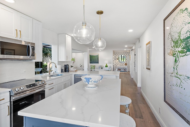 kitchen with sink, white cabinetry, a center island, hanging light fixtures, and appliances with stainless steel finishes