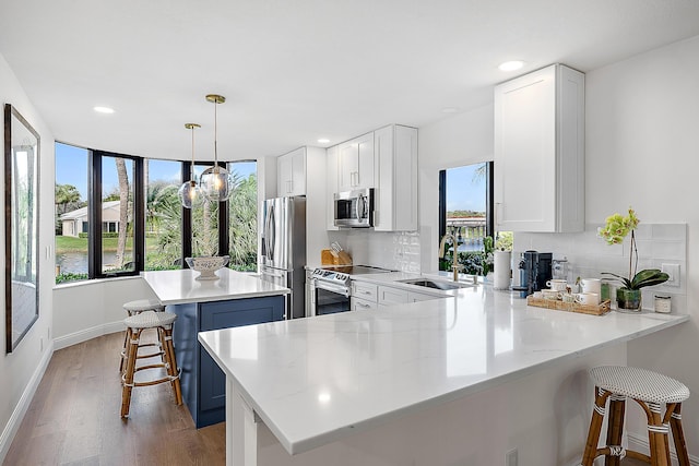 kitchen with appliances with stainless steel finishes, a breakfast bar, sink, hanging light fixtures, and kitchen peninsula