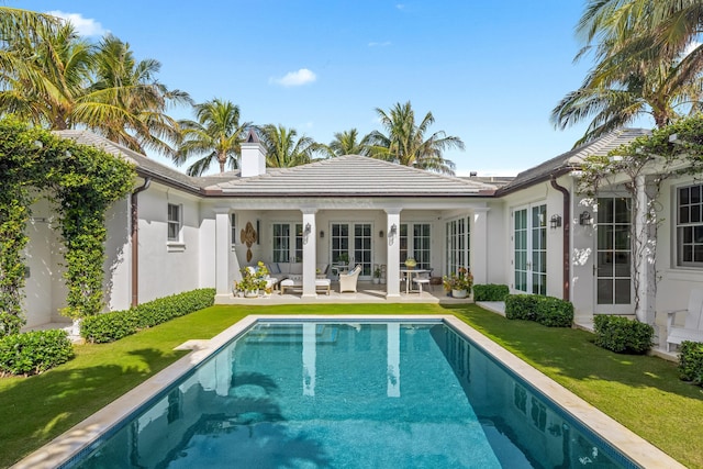 back of house featuring a yard, french doors, an outdoor pool, and stucco siding