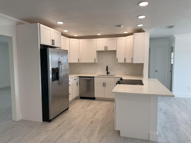 kitchen featuring white cabinetry, sink, kitchen peninsula, stainless steel appliances, and light stone countertops