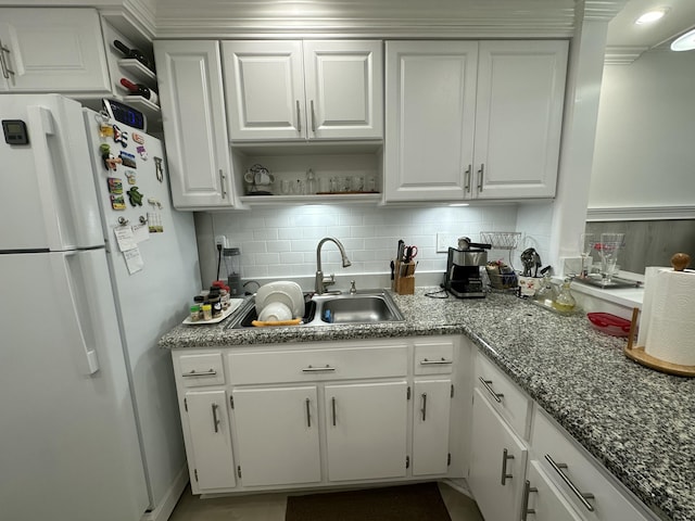 kitchen featuring white refrigerator, sink, white cabinets, and decorative backsplash