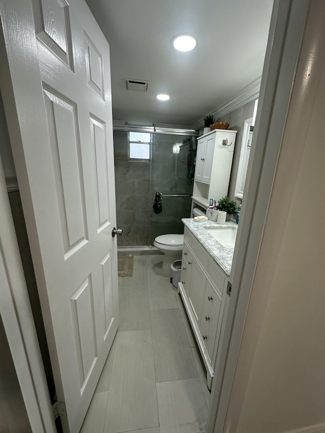 bathroom with vanity, ornamental molding, an enclosed shower, and toilet