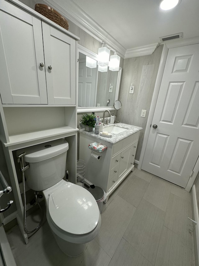 bathroom with crown molding, vanity, and toilet