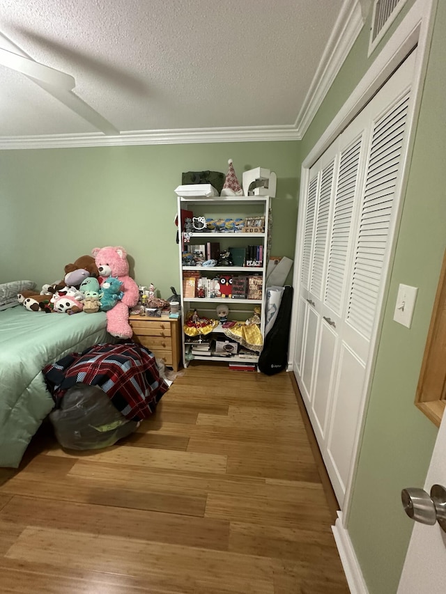 bedroom featuring wood-type flooring, ornamental molding, ceiling fan, a textured ceiling, and a closet