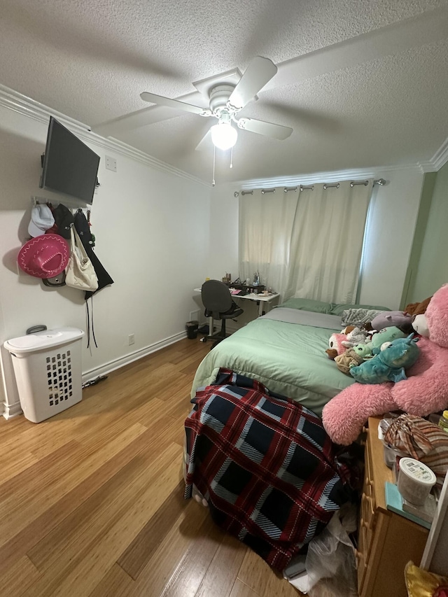 bedroom featuring wood-type flooring, ornamental molding, ceiling fan, and a textured ceiling