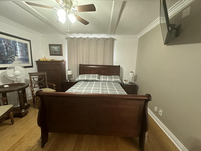 bedroom featuring hardwood / wood-style flooring, ornamental molding, ceiling fan, and a textured ceiling