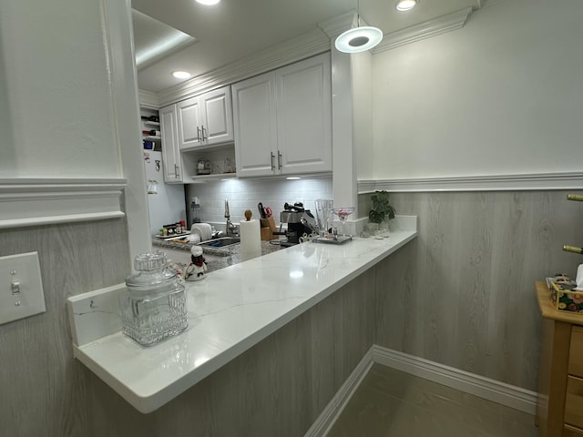 kitchen with pendant lighting, light stone countertops, tasteful backsplash, and white cabinets