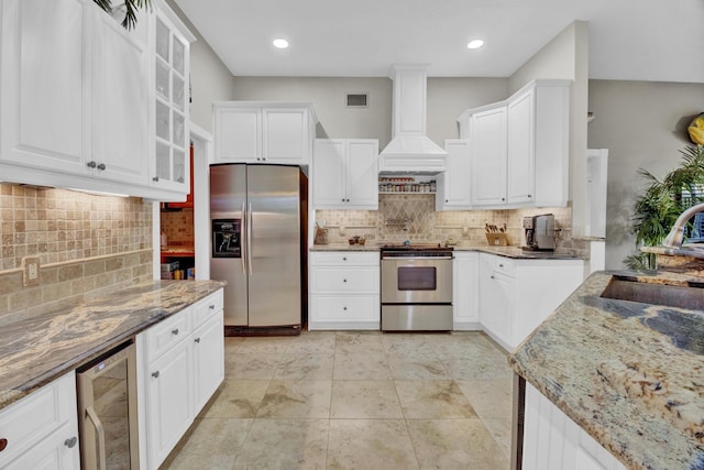 kitchen featuring stone counters, white cabinetry, sink, custom exhaust hood, and stainless steel appliances