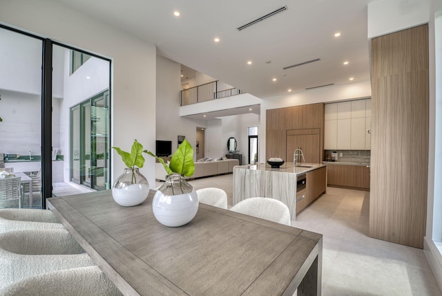 dining space featuring a healthy amount of sunlight, sink, and a high ceiling