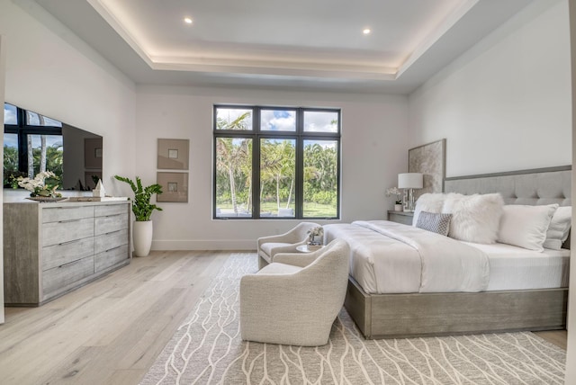 bedroom with a tray ceiling and light hardwood / wood-style flooring