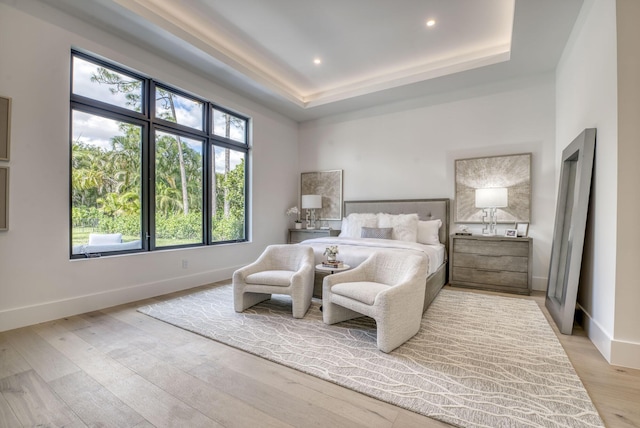 bedroom featuring a tray ceiling and light hardwood / wood-style flooring