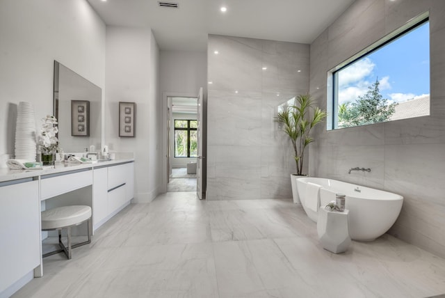 bathroom with vanity, a bathing tub, and tile walls