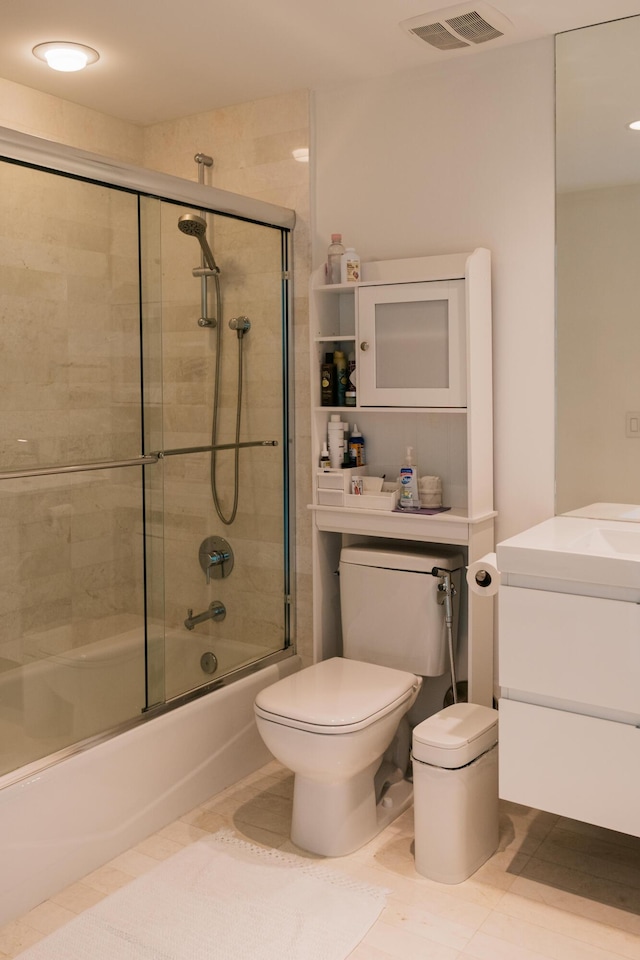 full bathroom featuring vanity, bath / shower combo with glass door, tile patterned floors, and toilet