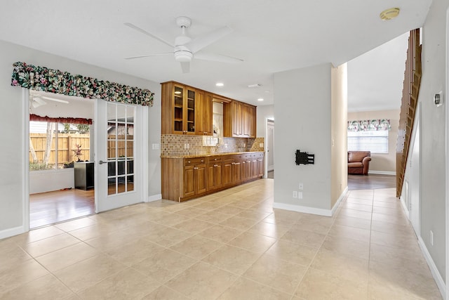 kitchen featuring backsplash, light tile patterned floors, light stone countertops, and ceiling fan